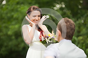 Happy couple standing in green park, kissing, smiling, laughing