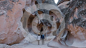 Happy couple standing near cave houses surrounded by fairy chimneys at Pasabag Valley in Turkey