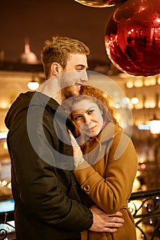 Happy couple stands in an embrace on the street in the evening in the festive lights