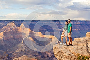 Happy couple on a steep cliff taking in the amazing view over famous Grand Canyon on a beautiful sunset, Grand Canyon