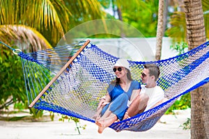 Happy couple on summer vacation relaxing in hammock