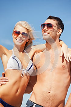 Happy couple in sunglasses on the beach