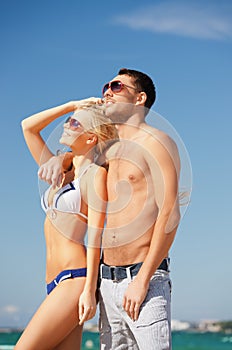 Happy couple in sunglasses on the beach