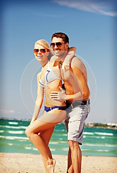 Happy couple in sunglasses on the beach