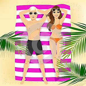 Happy couple with sunglasses lying on colorful beach towel