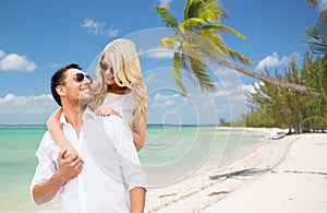 Happy couple in sunglasses over summer beach