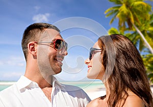 Happy couple in sunglasses over tropical beach
