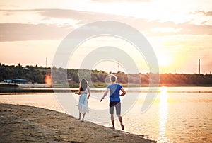 A happy couple on a sunset background running on the water. A man runs after a woman in a dress on a river with s