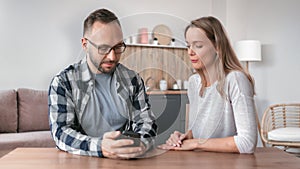 Happy couple surfing internet smartphone together discussing sitting at wooden table at cuisine