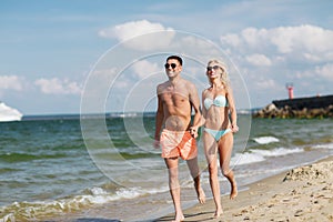 Happy couple in swimwear running on summer beach