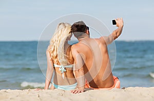 Happy couple in swimwear sitting on summer beach