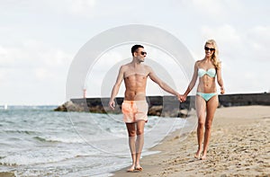 Happy couple in swimwear walking on summer beach