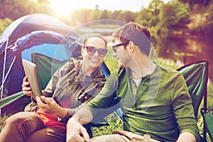 Happy couple with tablet pc at camping tent