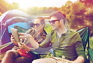 Happy couple with tablet pc at camping tent