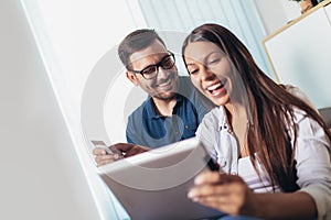 Happy couple with tablet pc computer and credit or bank card shopping online at home