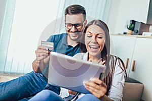 Happy couple with tablet pc computer and credit or bank card shopping online at home