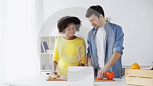 Happy couple with tablet pc cooking food at home