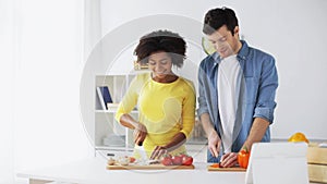 Happy couple with tablet pc cooking food at home