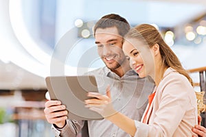 Happy couple with tablet pc taking selfie in mall