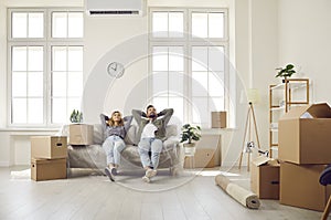 Happy couple take break and sit on couch while moving in their newly bought house