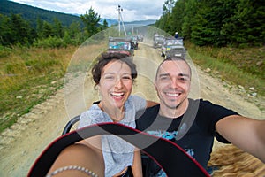 Happy couple take selfie standing on car durring mountain car tour