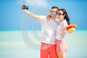 Happy couple taking a photo on white beach on honeymoon holiday