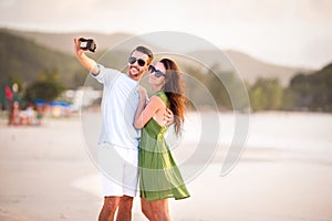 Happy couple taking a photo on white beach on honeymoon holidays