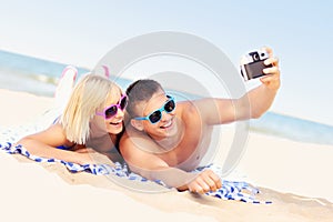 Happy couple taking pictures at the beach