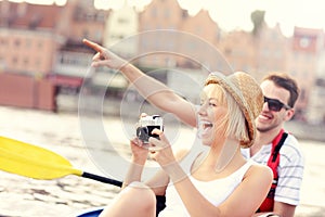 Happy couple taking pictures in a canoe