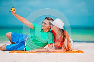 Happy couple taking a self photo on a beach on holidays