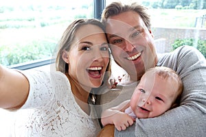 Happy couple taking a selfie with baby