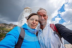 Happy couple taking selfie on the background of the lighthouse