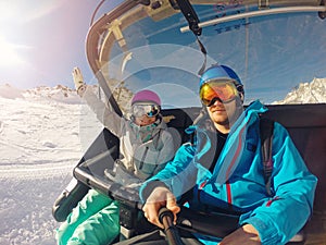 Happy couple taking selfie in chairlift at ski resort