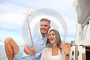 Happy couple taking a selfie after engagement proposal at sailing boat, relaxing on a yacht at the sea. photo