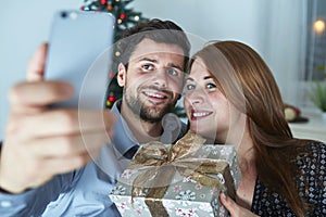 Happy couple is taking a selfie with gift