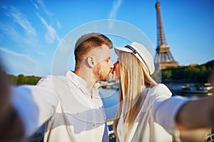 Happy couple taking selfie near the Eiffel tower