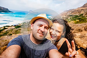 Happy couple taking selfie photo with island and turquoise water. Self portrait of couples in vacation