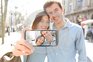 Happy couple taking selfie showing blank phone screen