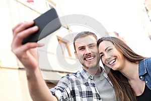Happy couple taking selfies with smartphone in the street