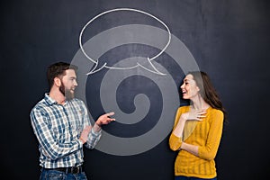 Happy couple talking over chalkboard background with drawn dialogue