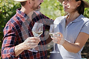 happy couple tasting white wine in vineyard