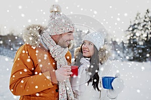 Happy couple with tea cups over winter landscape