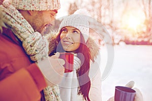 Happy couple with tea cups over winter landscape