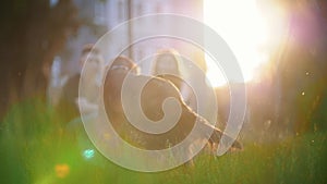 Happy couple with their dogs having a rest on the grass at summer sunset