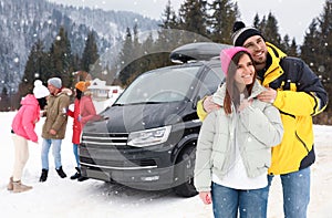 Happy couple and their friends near car on road. Winter vacation