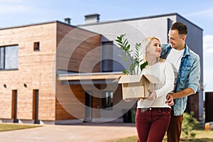 Happy couple with their new house at the background and smiling