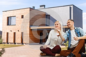 Happy couple with their new house at the background and smiling