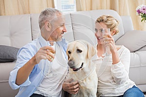 Happy couple with their pet dog drinking champagne