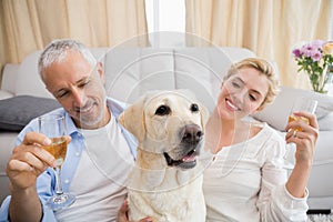 Happy couple with their pet dog drinking champagne