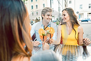 Happy couple toasting with their mutual female friend at a trendy restaurant